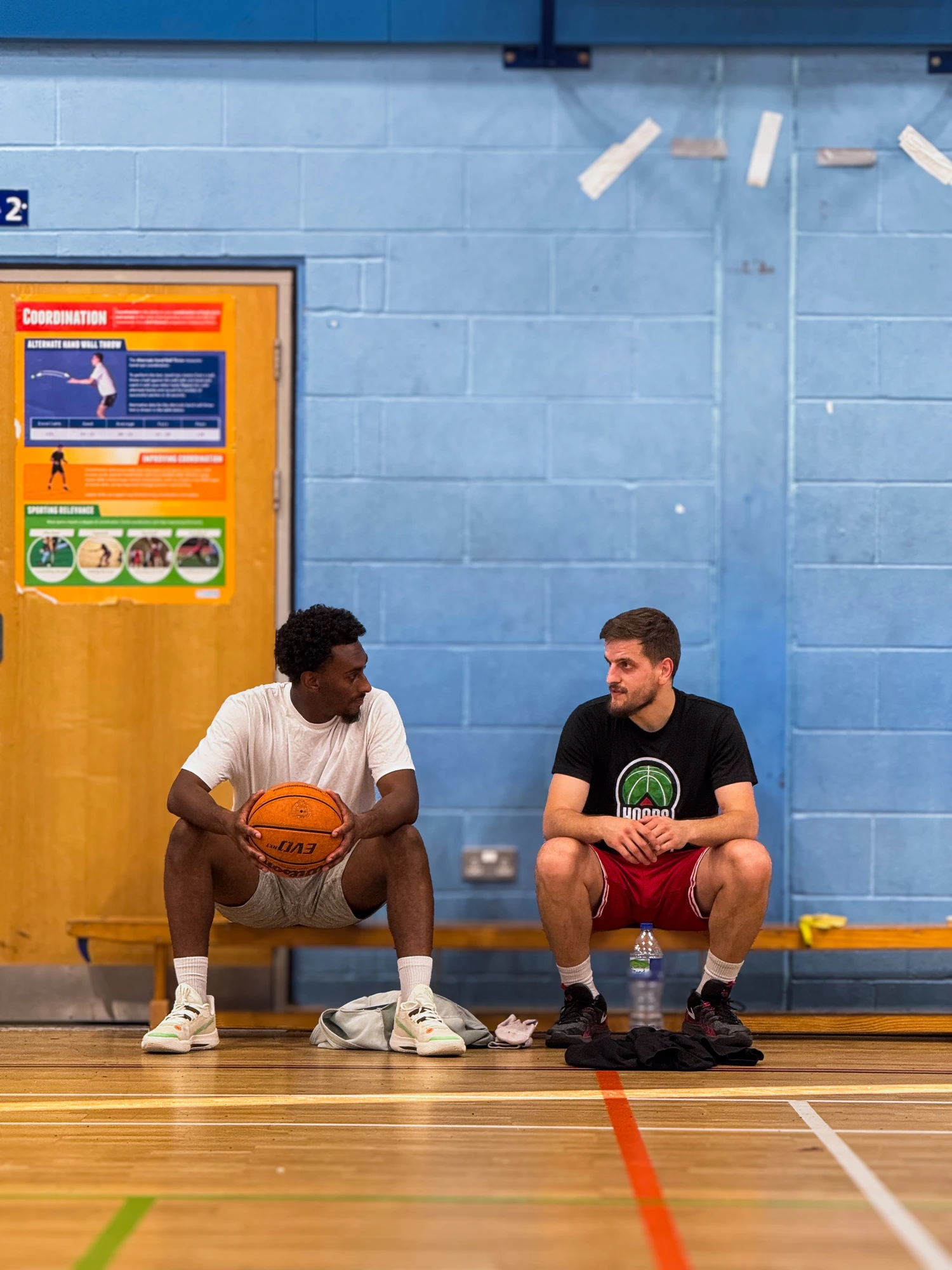 Two athletes talking on the bench between reps