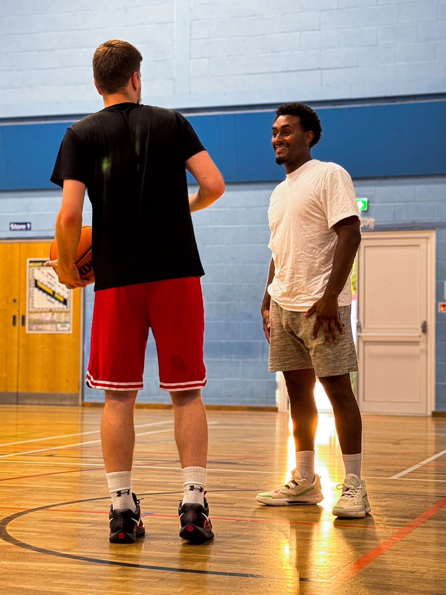 Coach and athlete talking on court in the sunlight